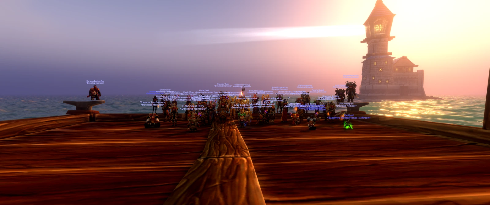 Guild members posing on a wooden dock as a lighthouse beam crosses the sunset sky.